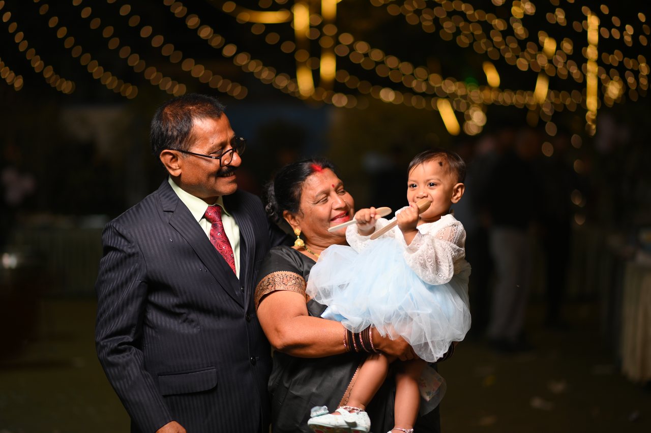 Grandparents laugh with their granddaughter at her first birthday party