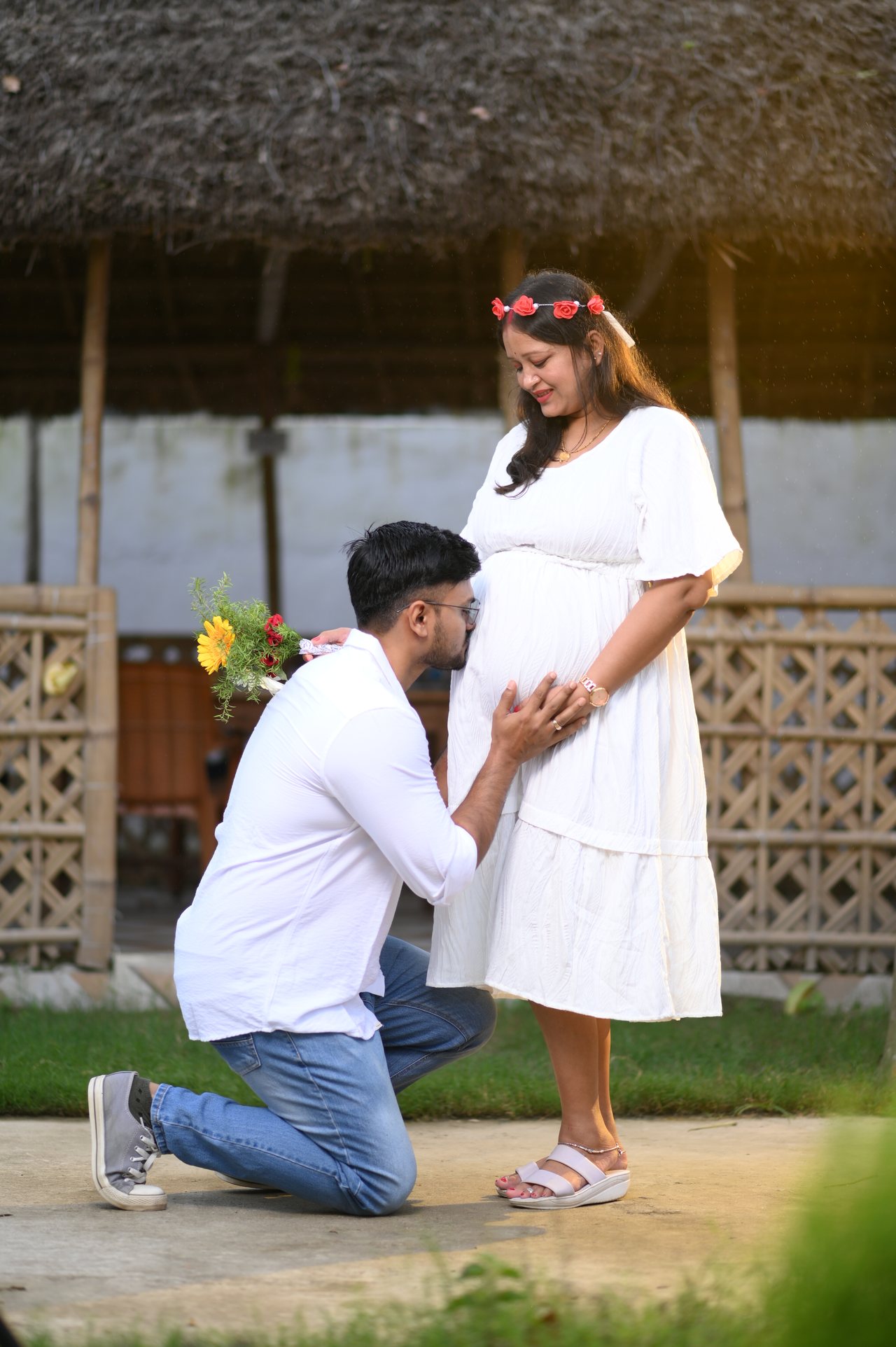 A father-to-be kneels to listen to the bump while she smiles down