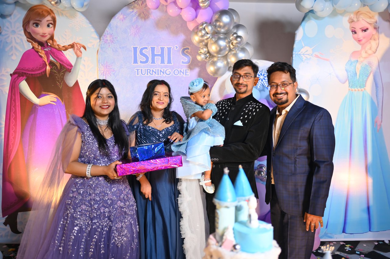 Family and friends gather around a first birthday cake
