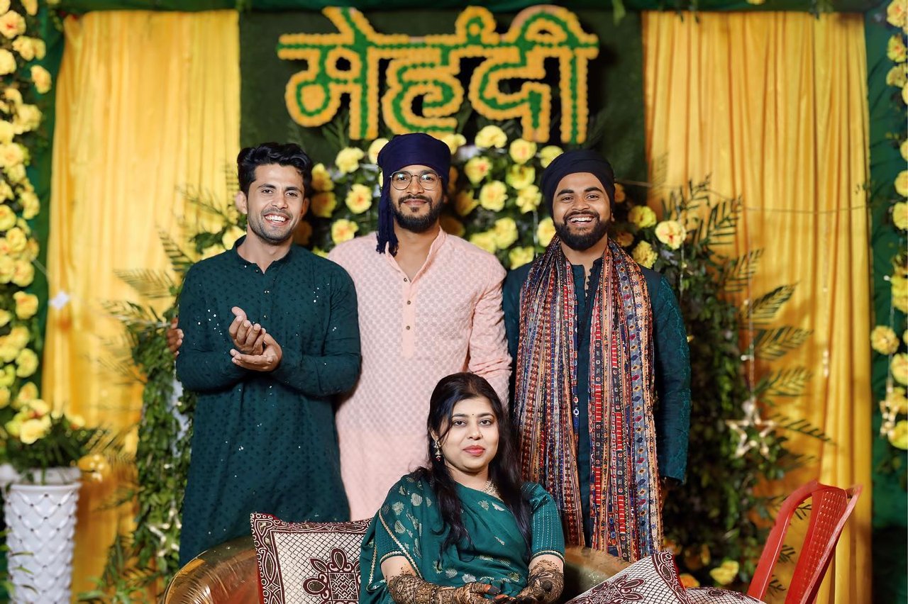 A family gathered on the mehendi stage beneath a marigold sign
