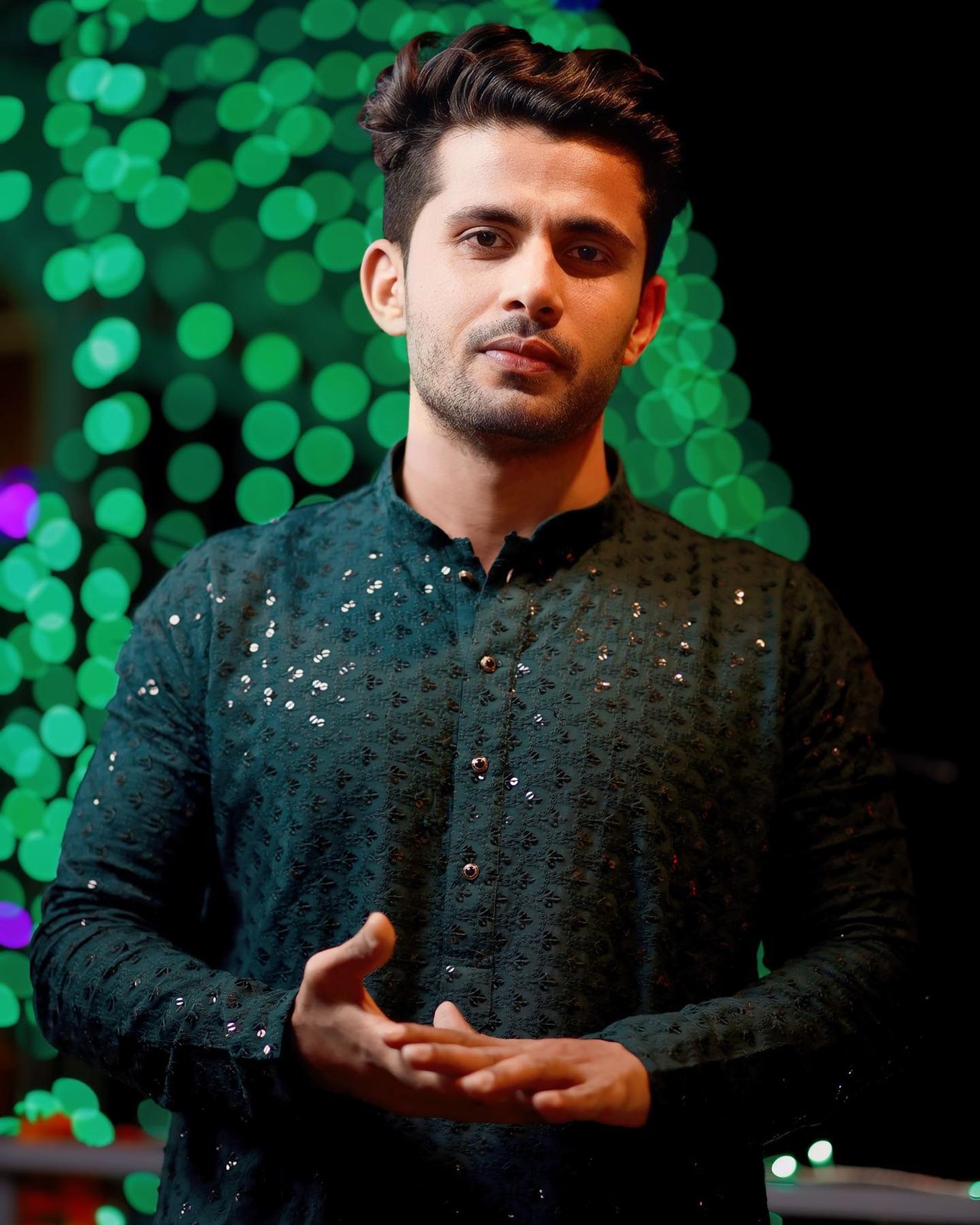 Portrait of a groom in a dark green kurta against glowing bokeh