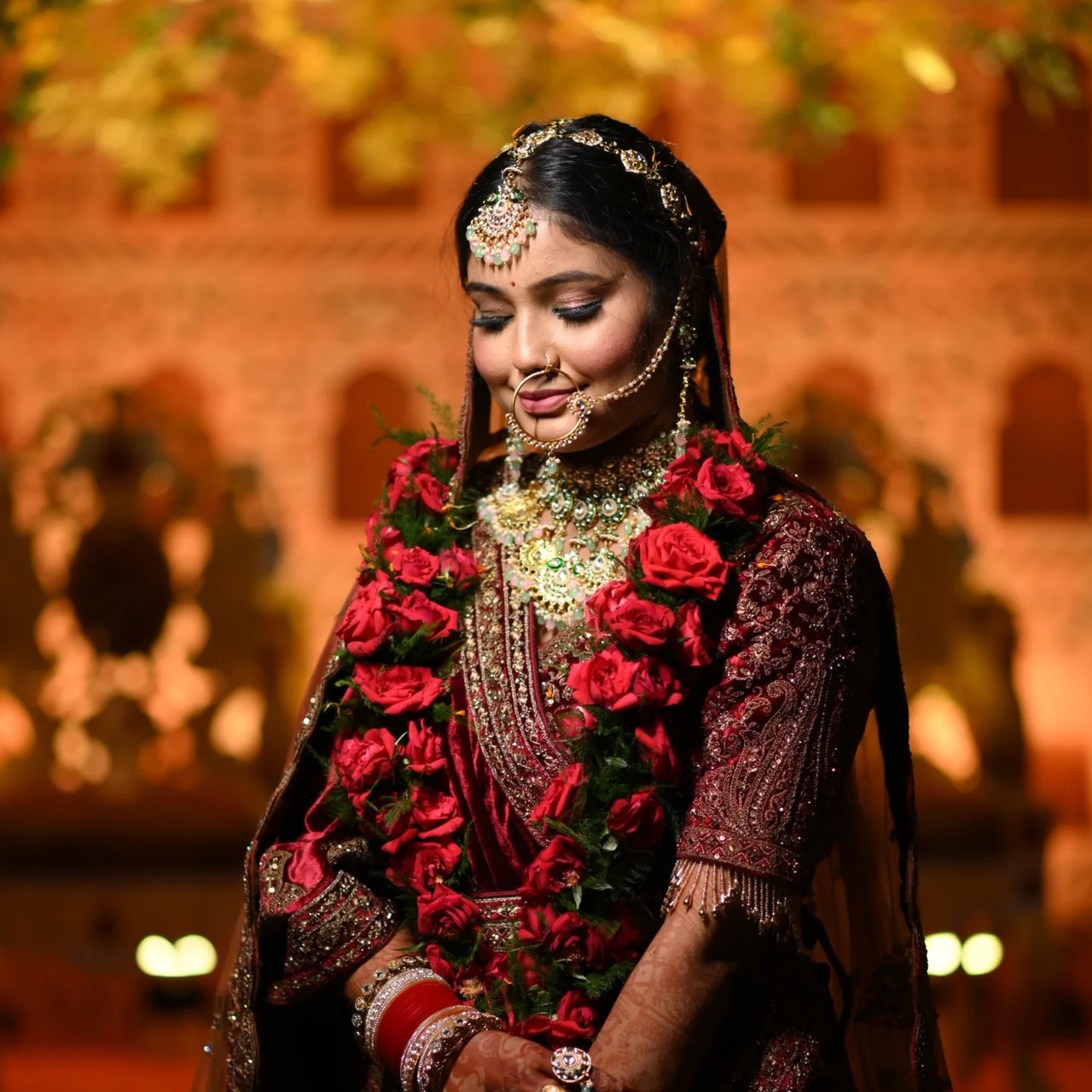 Portrait of a bride in red with heavy jewellery, warm lights behind