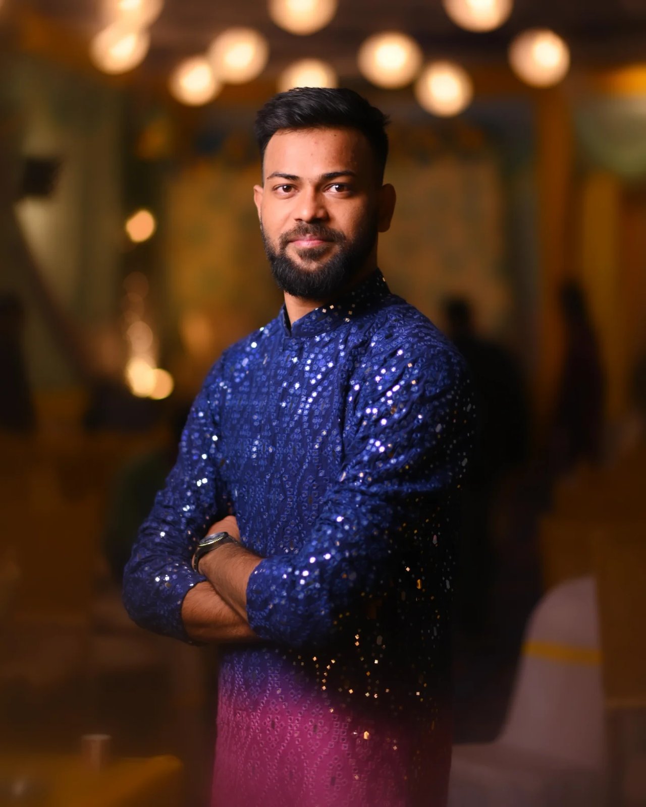 Portrait of a groom in a blue sequinned sherwani among warm lights