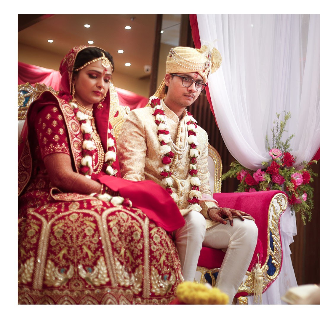 Bride and groom seated on a white and red wedding stage
