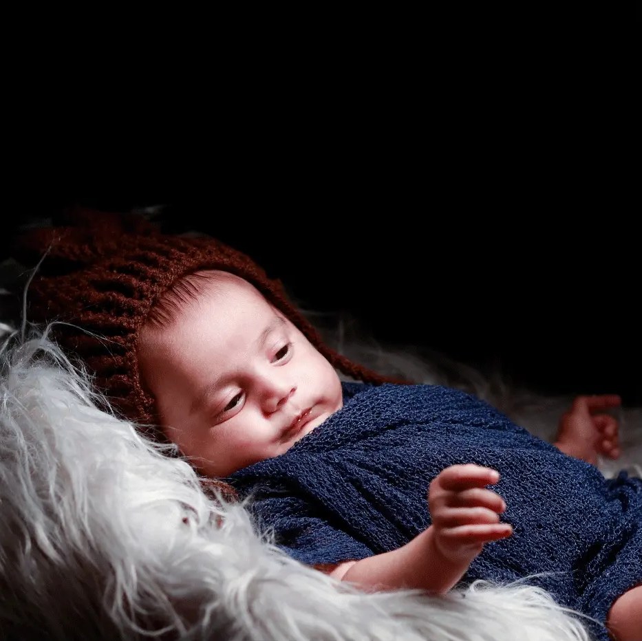 A newborn in a knitted outfit asleep on soft fur
