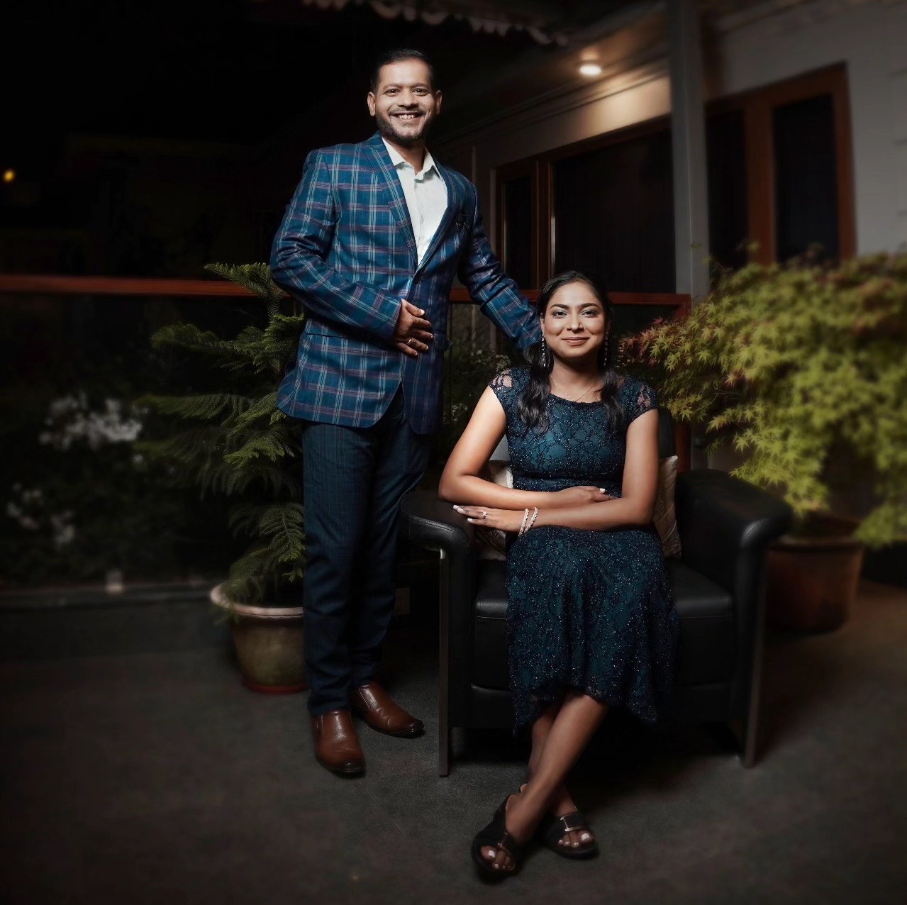 A couple pose on a terrace at night, softly lit