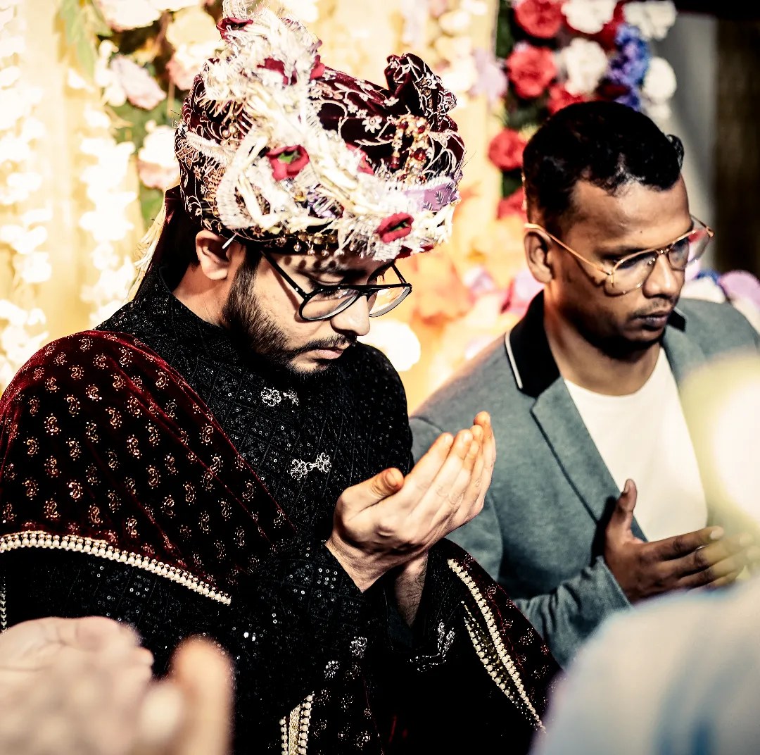 A groom prays with folded hands during the ceremony
