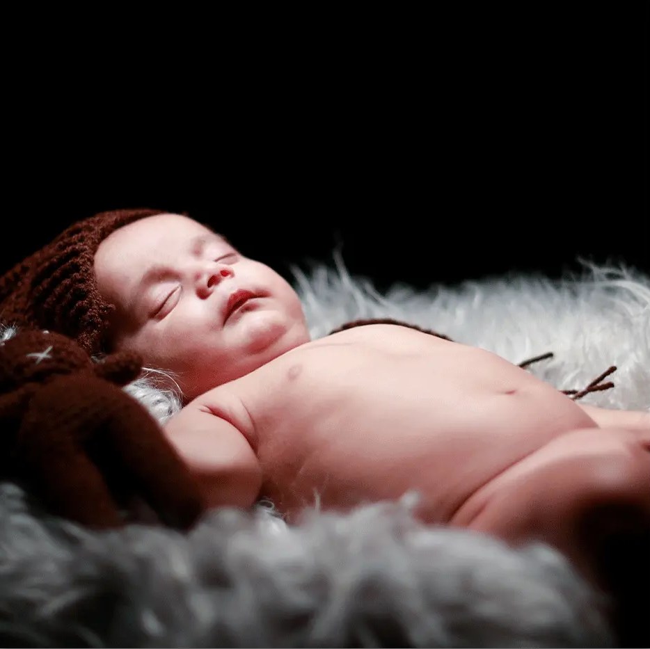 A newborn sleeps peacefully on soft grey fur