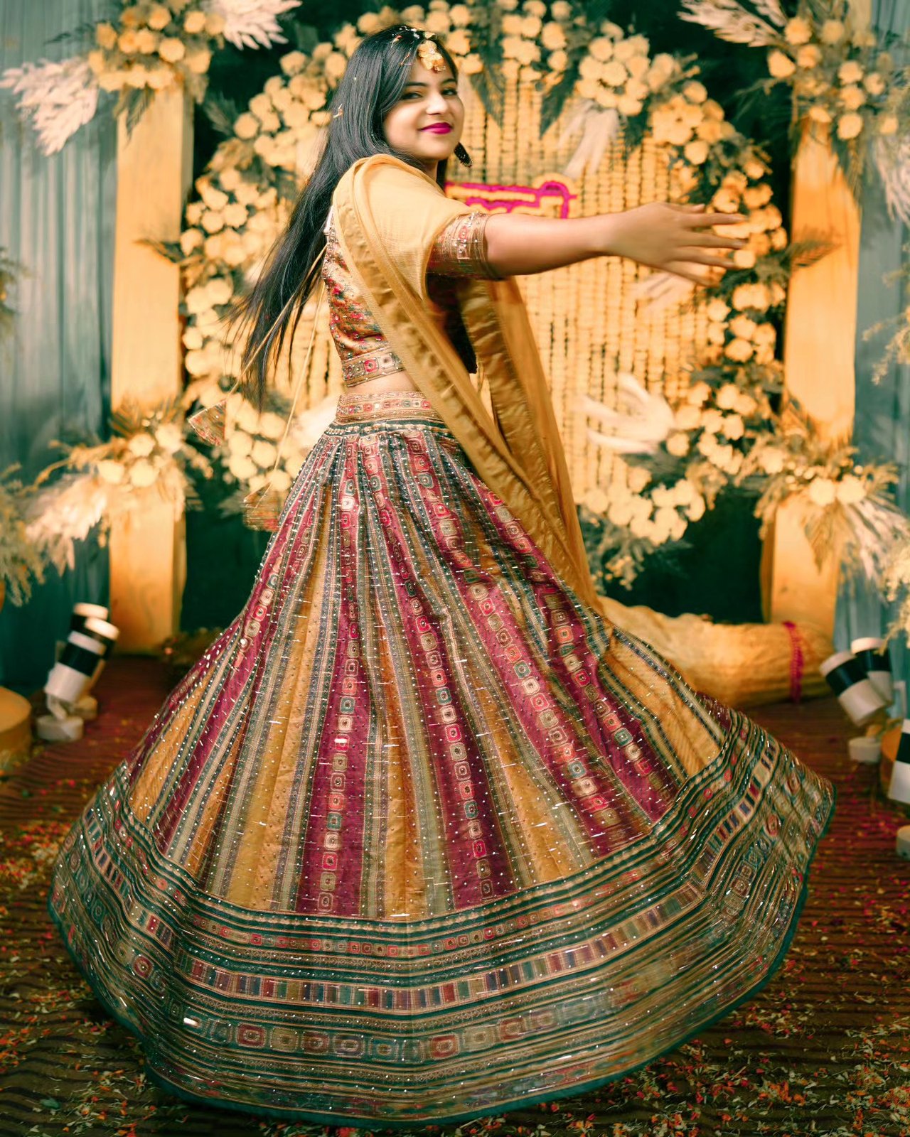 A bride twirls in a striped lehenga before a decorated stage