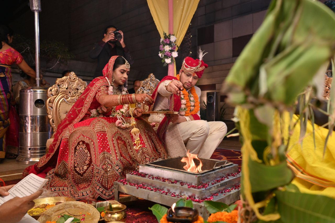 Bride and groom seated before the sacred fire under a decorated mandap