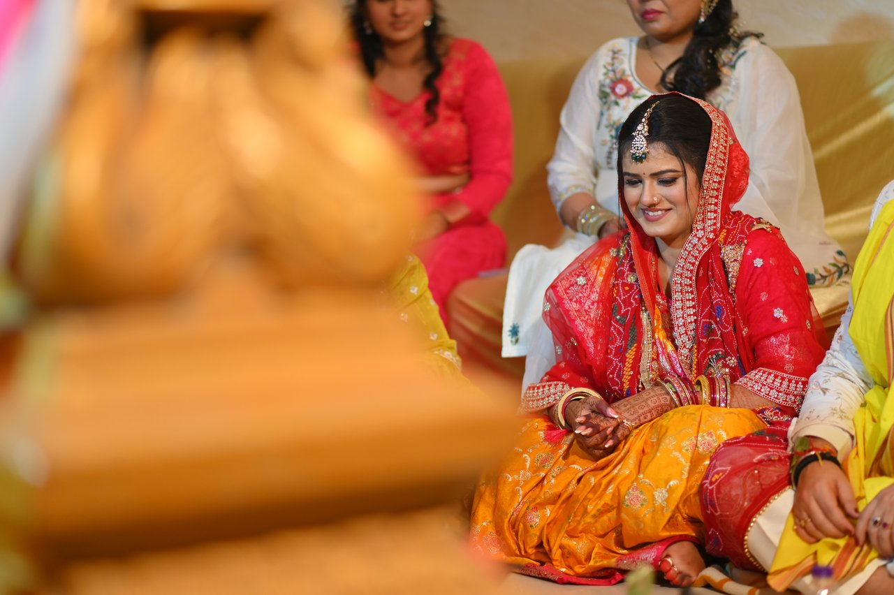 A smiling bride seated among family during a ritual