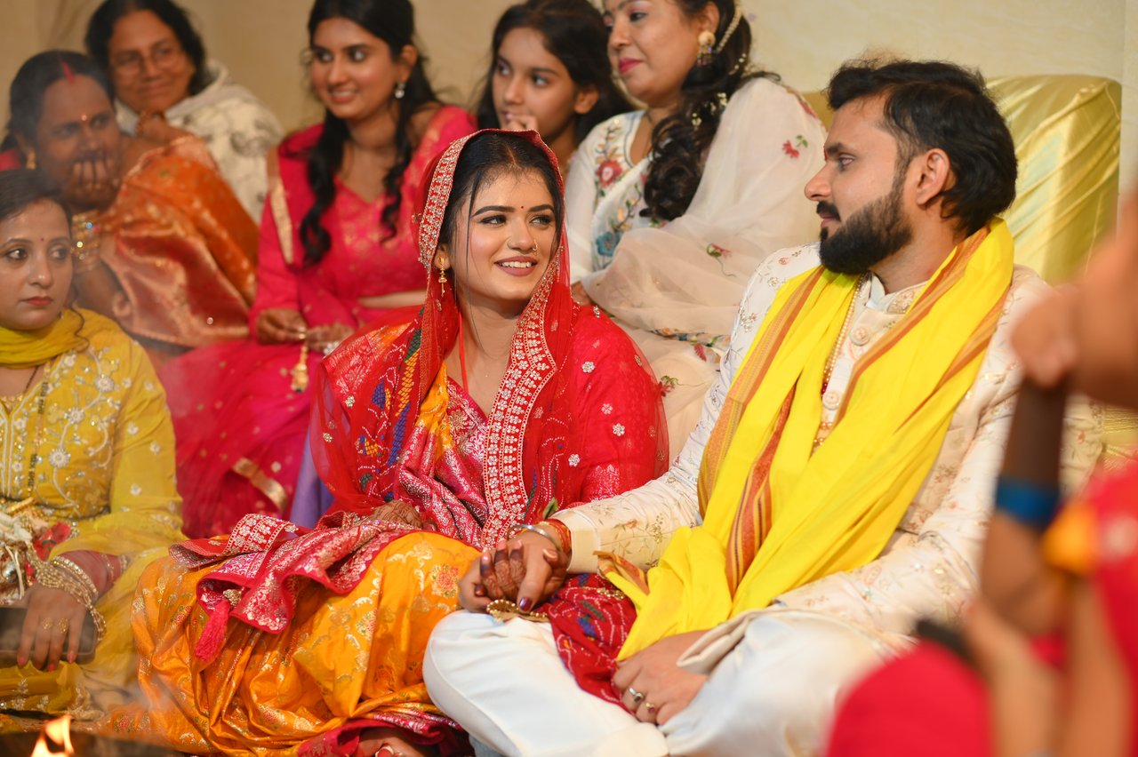 Bride and groom seated together among family, smiling