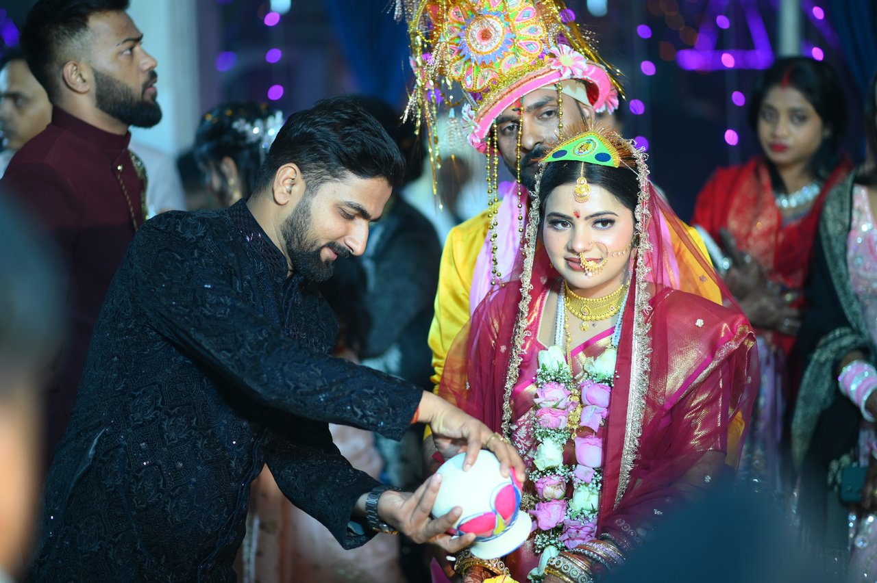 A relative helps the bride during the ceremony while the groom watches