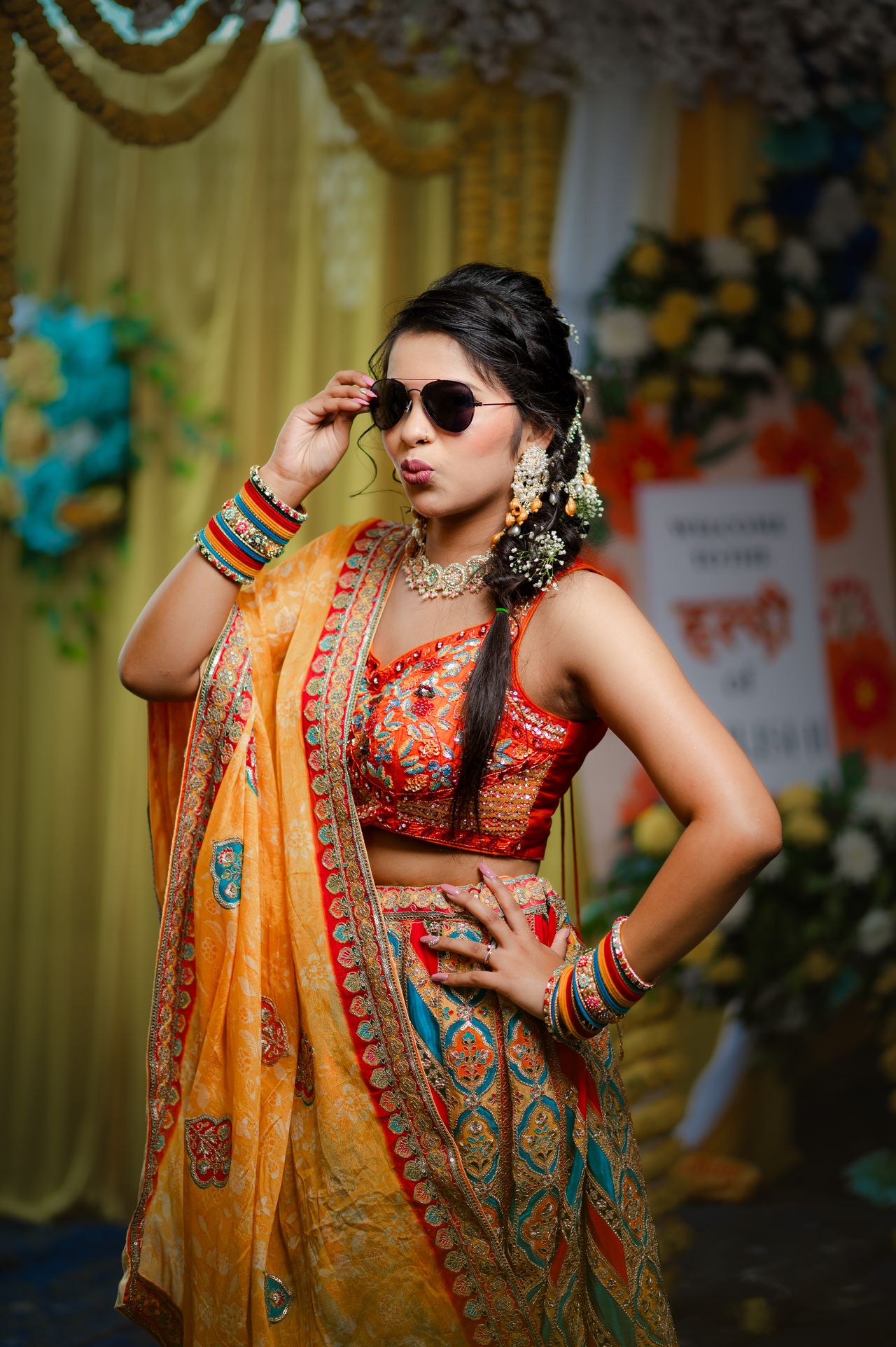 Bride at her haldi striking a playful pose in sunglasses