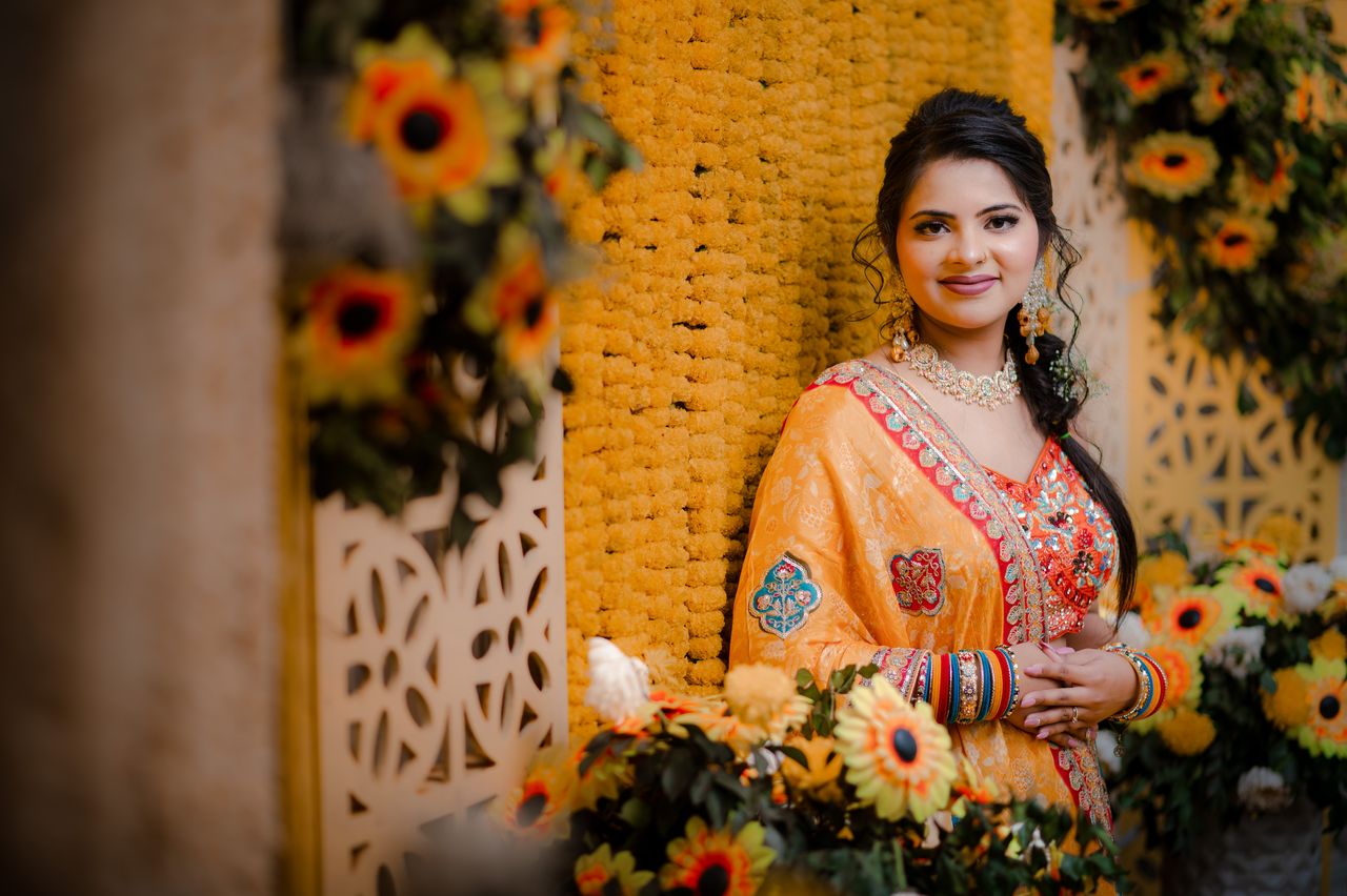 Bride framed by sunflowers and marigolds at her haldi