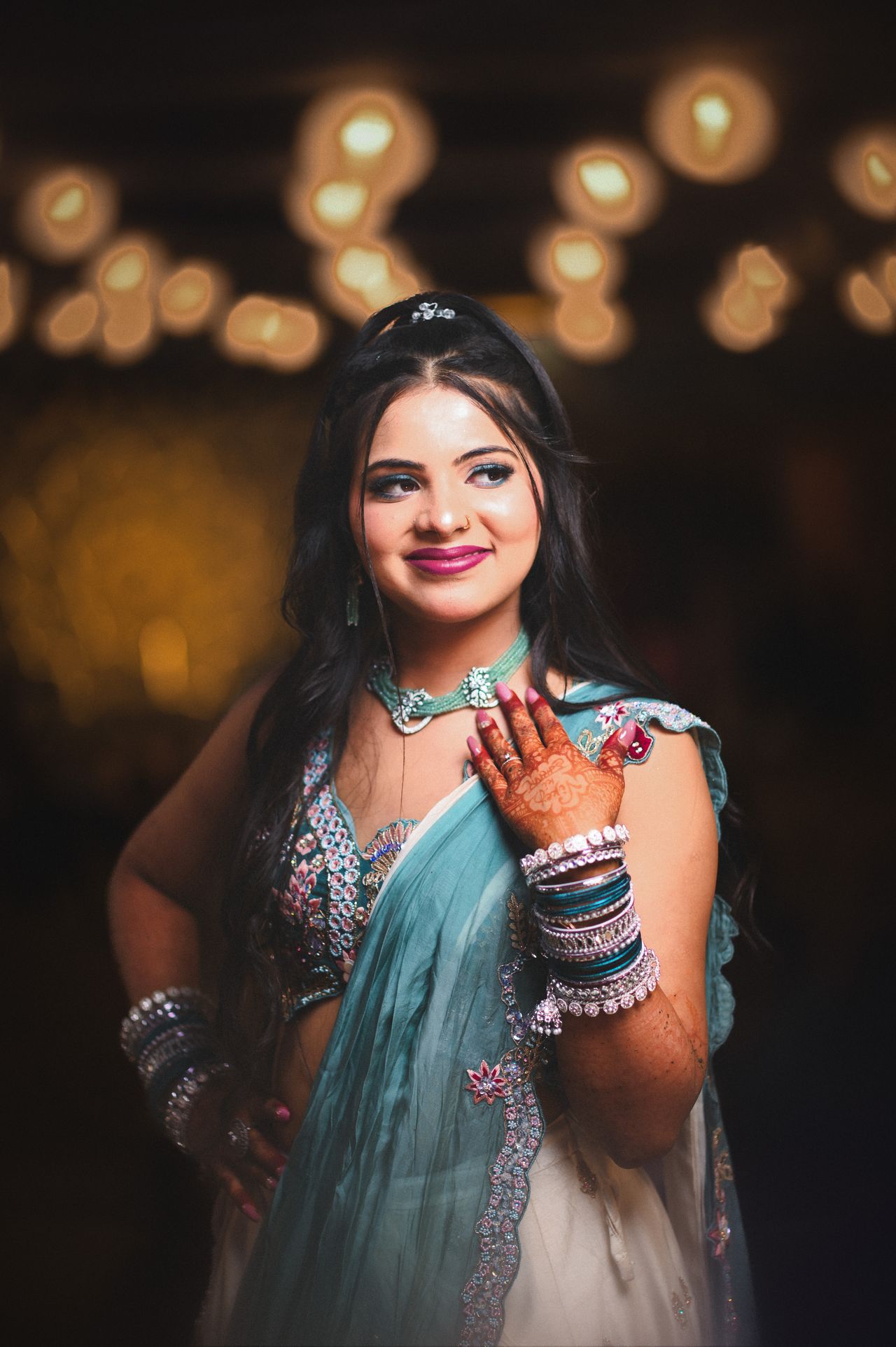 Bride in teal laughing, warm bokeh lights behind her