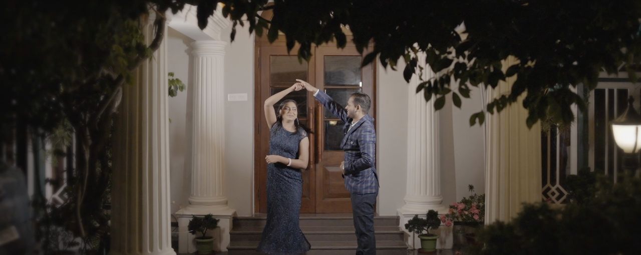 A couple twirling on the steps of a colonial house at dusk