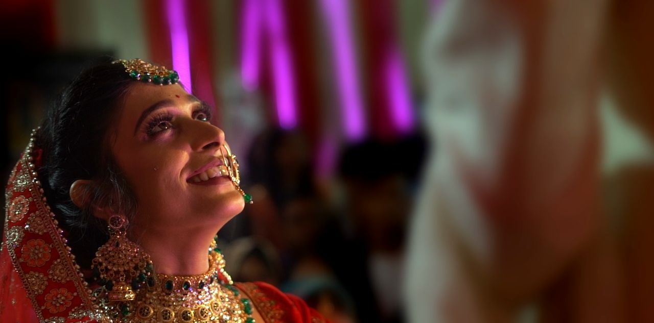 A bride laughs as she looks up, the lights blurring behind her
