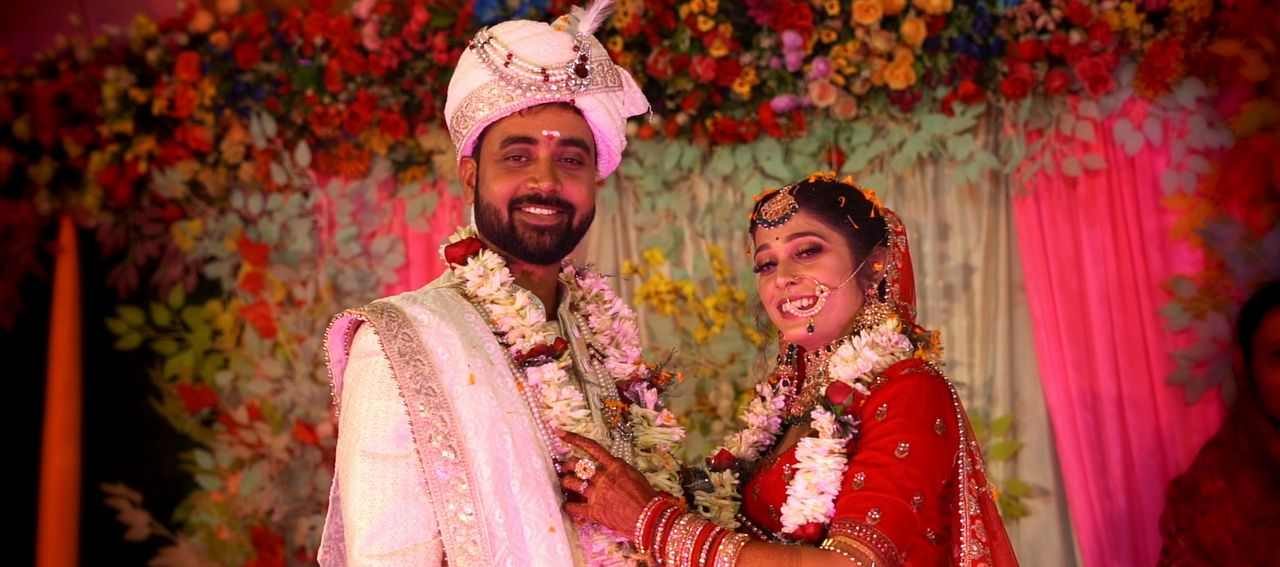 Bride and groom in garlands smiling on a floral stage